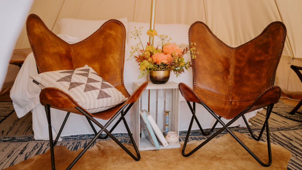 rustic looking leather chairs with a throw pillow in an outdoor tent